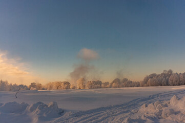 Winter landscape with a snow-covered field in the rays of the setting sun
