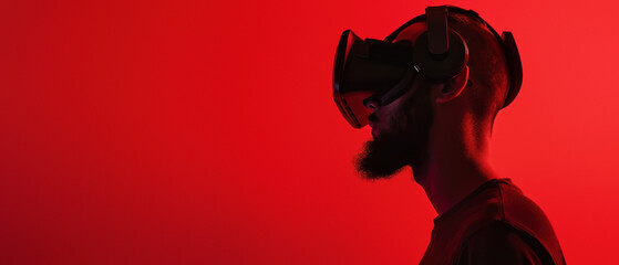 Silhouette of a male wearing a virtual reality headset, highlighted against a vibrant red backdrop forming a striking contrast - 749289232