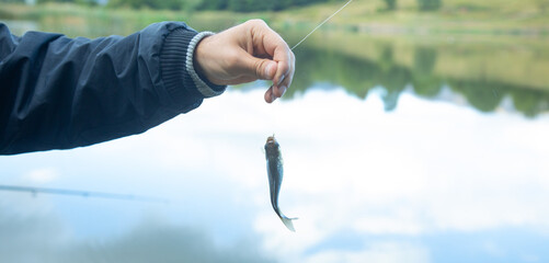 Man catching and showing small fish in the lake.