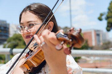 portrait of young latin woman violinist making music on street