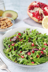 A plate with green rocket salad with pomegranate and avocado