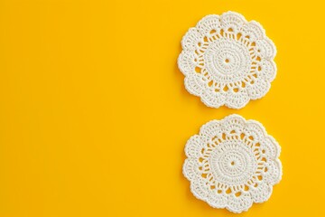 White crochet doilies on a yellow background with copy space. - obrazy, fototapety, plakaty