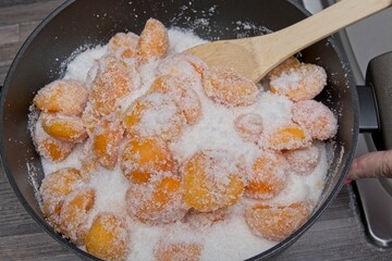 Using a spoon to mix the apricot pieces and sugar