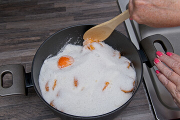 Using a spoon to start mixing the fruit and sugar