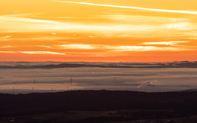 Morning mood with fog in the valley and sunrise colors in the dramatic sky. Landscape view in Austria.