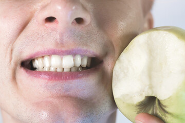 Man is smiling with teeth and eating apple. Close up, man's mouth and lips. Healthy lifestyle, healthy food. Vitamins for white healthy teeth.