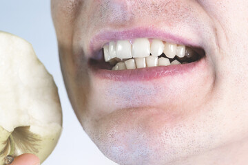 Man is smiling with teeth and eating apple. Close up, man's mouth and lips. Healthy lifestyle, healthy food. Vitamins for white healthy teeth.