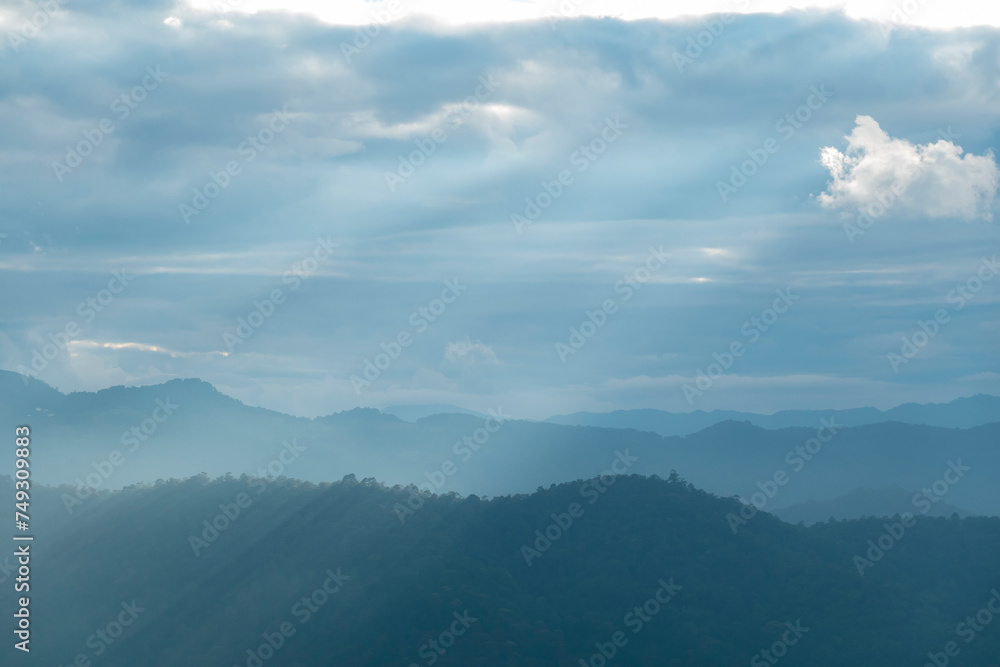 Wall mural sun rays filter through the clouds in hills of the valley illuminated by the sun's rays filtering th