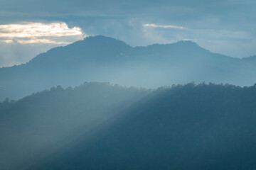 Sun rays filter through the clouds in hills of the valley illuminated by the sun's rays filtering through the clouds