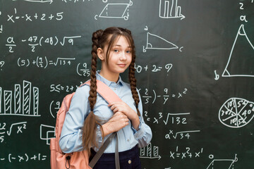 Teenage Girl with School Bag Standing at the Blackboard. Portrait of schoolgirl 10 - 12 years old.
