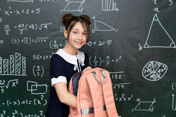 Teenage Girl with School Bag Standing at the Blackboard. Portrait a schoolgirl 10 - 12 years old.