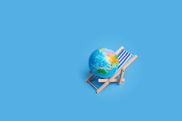 Chaise longue with Earth, summer trip planning, global vacation, beach relaxation,blue background