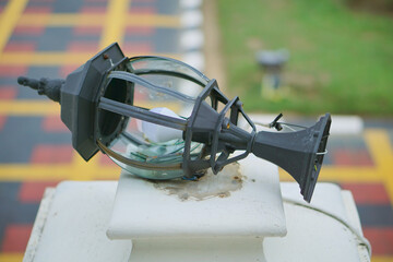 a broken fence lamp made of iron and glass      