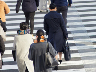 冬の朝の街の交差点の横断歩道を渡る人々の姿