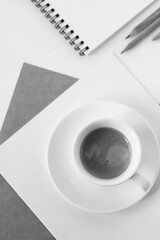 Monochrome Business Mockup. Office Desk Flatlay with Cup of Coffee, Sheets of Paper, Notebook, Pencil on White Background. 