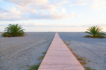 Wooden decking in the form of a path on the sea beach at sunset.