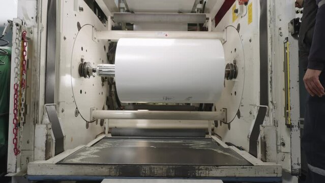 The placement of the raw label roll into the labeling machine at the label factory.