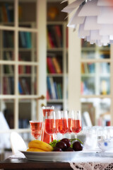 Red, wine and fruit on dinner table, celebration glasses for holiday and party in home living room. Hospitality, guest preparation with alcohol beverage, bookshelf and vacation event or entertainment