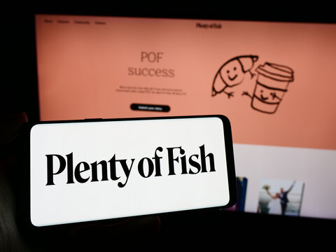 Stuttgart, Germany - 02-26-2024: Person holding mobile phone with logo of Canadian online dating company Plentyoffish Media ULC in front of web page. Focus on phone display.