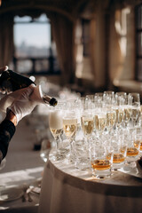 The waiter fills the glass with champagne. Catering, welcome drink, service, alcohol. A solemn event
