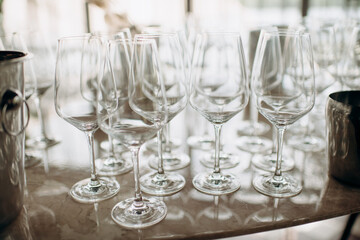 Many empty champagne or wine glasses sparkle in the sun. Preparation for a reception or holiday, a container for alcoholic beverages. Restaurant, catering, service