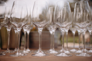 Many empty champagne or wine glasses sparkle in the sun. Preparation for a reception or holiday, a container for alcoholic beverages. Restaurant, catering, service