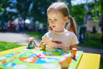 preschooler girl playing board game outdoors