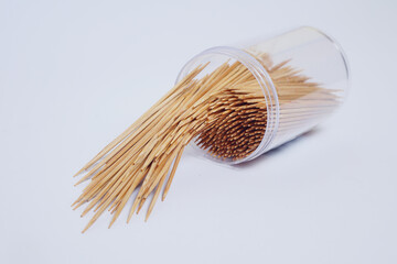 a collection of toothpicks in a cylindrical plastic container on a white background