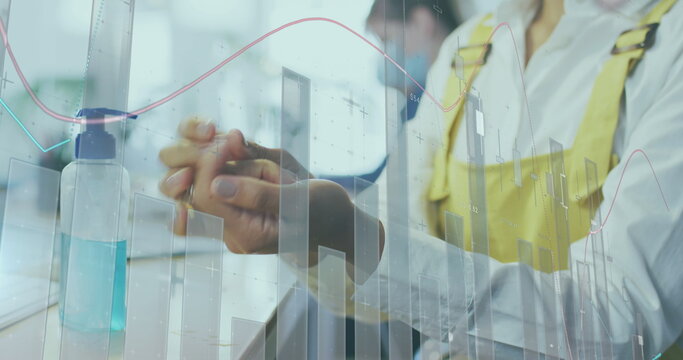 Image of financial data processing over businesswoman disinfecting hands - Powered by Adobe