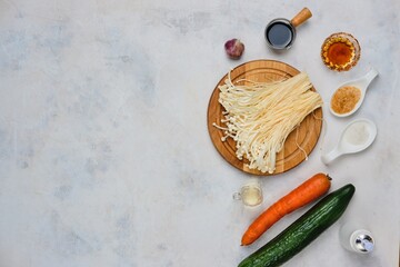 Prepared ingredients for cooking salad with enoki mushrooms., Golden threads on a light concrete background. Chinese cuisine.