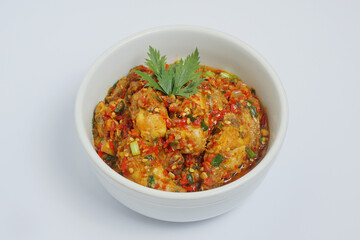 Rica-rica chicken wings decorated with celery leaves in a white bowl on a white background   