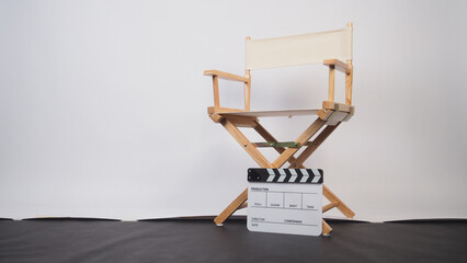 White director chair with clapper board on white background and black floor.