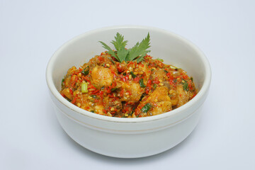 Rica-rica chicken wings decorated with celery leaves in a white bowl on a white background   