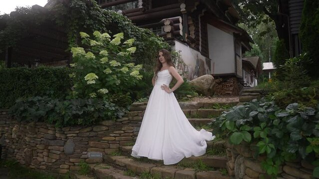 Bride in wedding dress poses on stairs in front of house