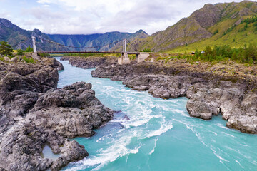 Suspension Oroktoysky bridge over Katun river in valley of Altai Mountains, aerial top view....