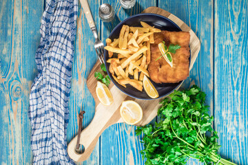 A piece of fried cod with fries on a plate.