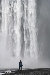 Close up of lower part of the Seljalandsfoss waterfall in Iceland with its origin in the volcano glacier Eyjafjallajokull; image filled with falling water and one person underneath
