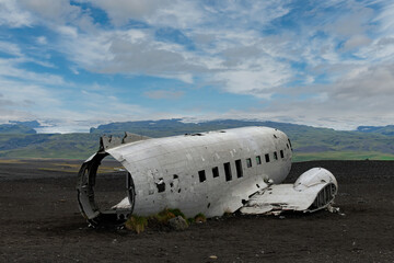 Close up view of demolished and vandalized Sólheimasandur plane wreck, remains of a 1973 U.S. Navy plane that crashed on the black sand close to Vik, Iceland, with Sólheimajökull glacier in background