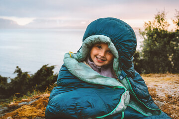 Child girl in sleeping bag camping gear morning in mountains active travel family vacations bivouac outdoor, traveler kid portrait active adventure eco tourism healthy lifestyle hobby - 749358232