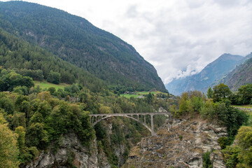 Fototapeta na wymiar Panoramic view over the Stalden, Switzerland landscape with the 1930, 108 meters long Visp or Stalden bridge from bridge designer, A. Sarrasin crossing a gorge in the Valais region 