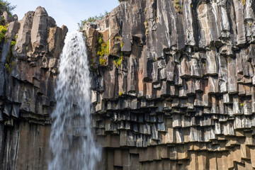 Low anglle close up view of water falling from the Svartifoss waterfall in Skaftafell in Vatnajökull National Park in Iceland with a base of sharp basalt hexagonal columns
