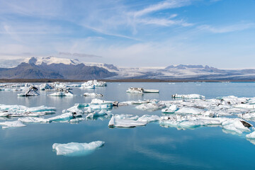 Panoramic view over the mirror like water of the glacial lagoon filled with icebergs of Fjallsarlon...