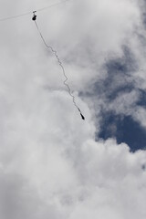 Silhouette of a person hanging on a cord during bungee jump in a open sky