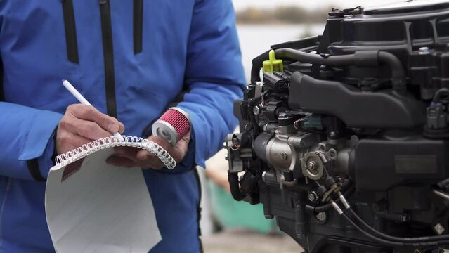 The master writes down in a notebook what parts he needs to buy to repair the outboard motor. Repair of two-stroke and four-stroke injection and carburetor engines.