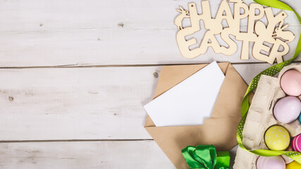 Art Happy Easter concept. Easter eggs, letter, greeting card and on white wooden background. Flat lay, top view, copy space.