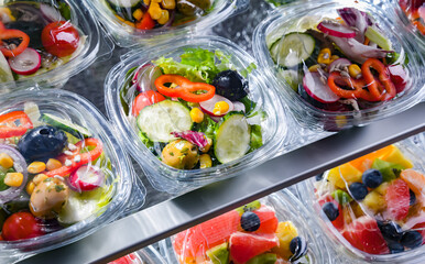 Boxes with pre-packaged vegetable salads in a commercial fridge