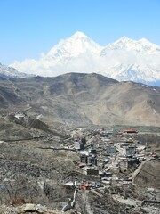 small town surrounded by snowy mountain with blue sky as background