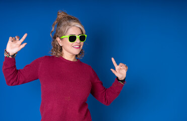 Pretty cheerful woman with green glasses on a blue background, image with copy space for text.