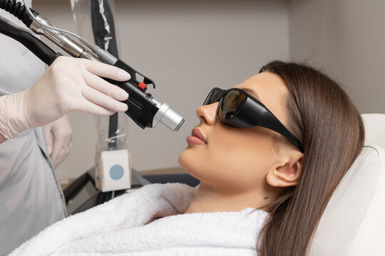 Cosmetologist make laser hair removal on woman's under nose