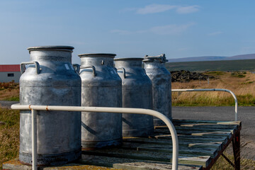 Close up view of some milk churns on a milk churn stand along one of the roads in agricultural area of Iceland with mountains and volcanic landscape in the background